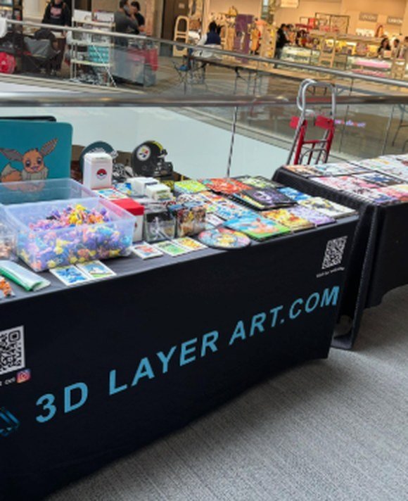 The 3D Layer Art table with keychains and prints on display
